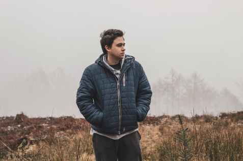 man wearing black zip up hooded jacket standing