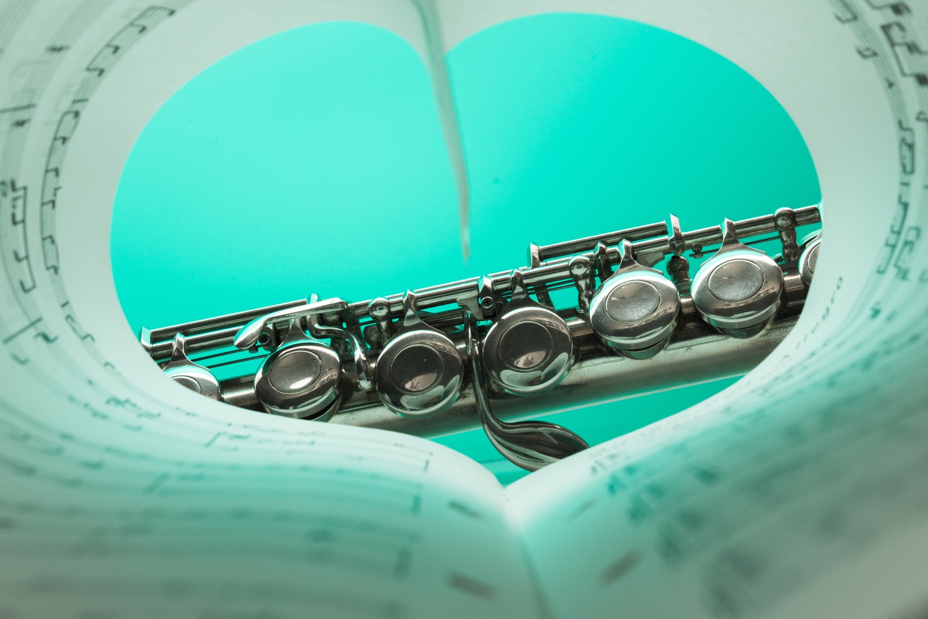 music note book and silver soprano flute close up photography
